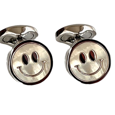 A pair of metal cufflinks in the shape of a smiling face emoji